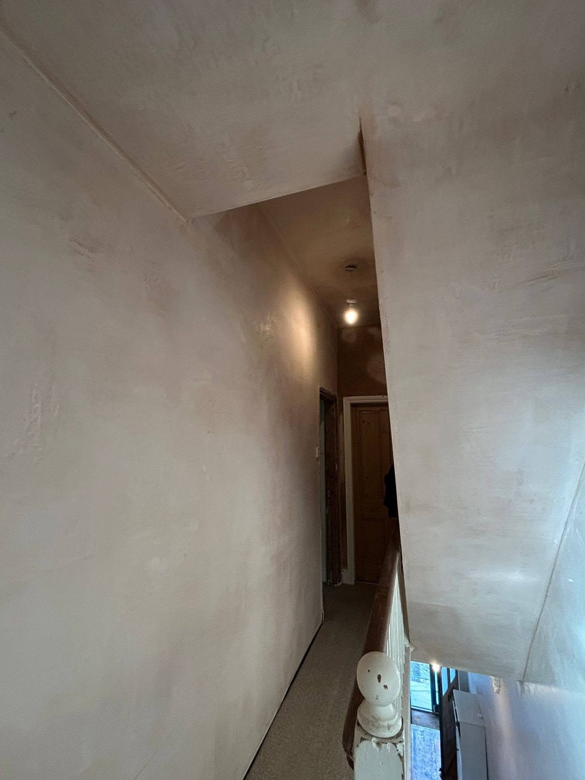 Narrow landing and stairwell with fresh pink plaster on the walls and ceiling