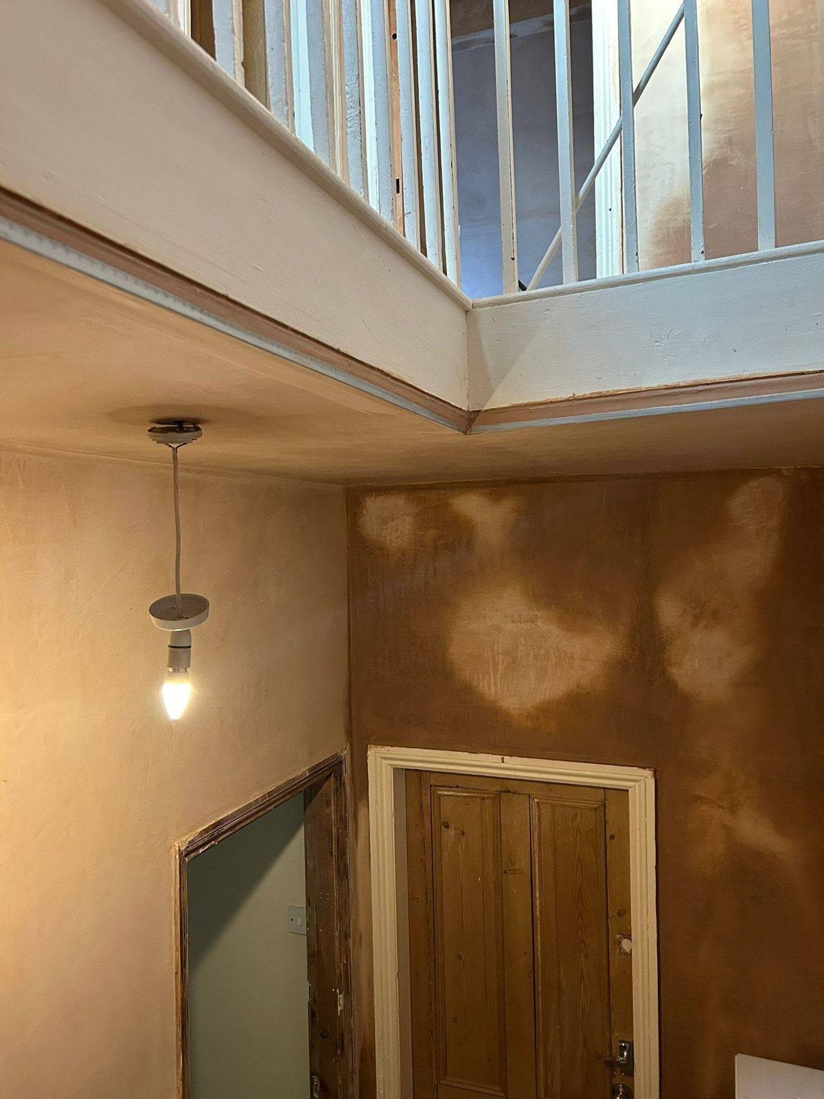 Stairwell and landing with new plaster drying in patches