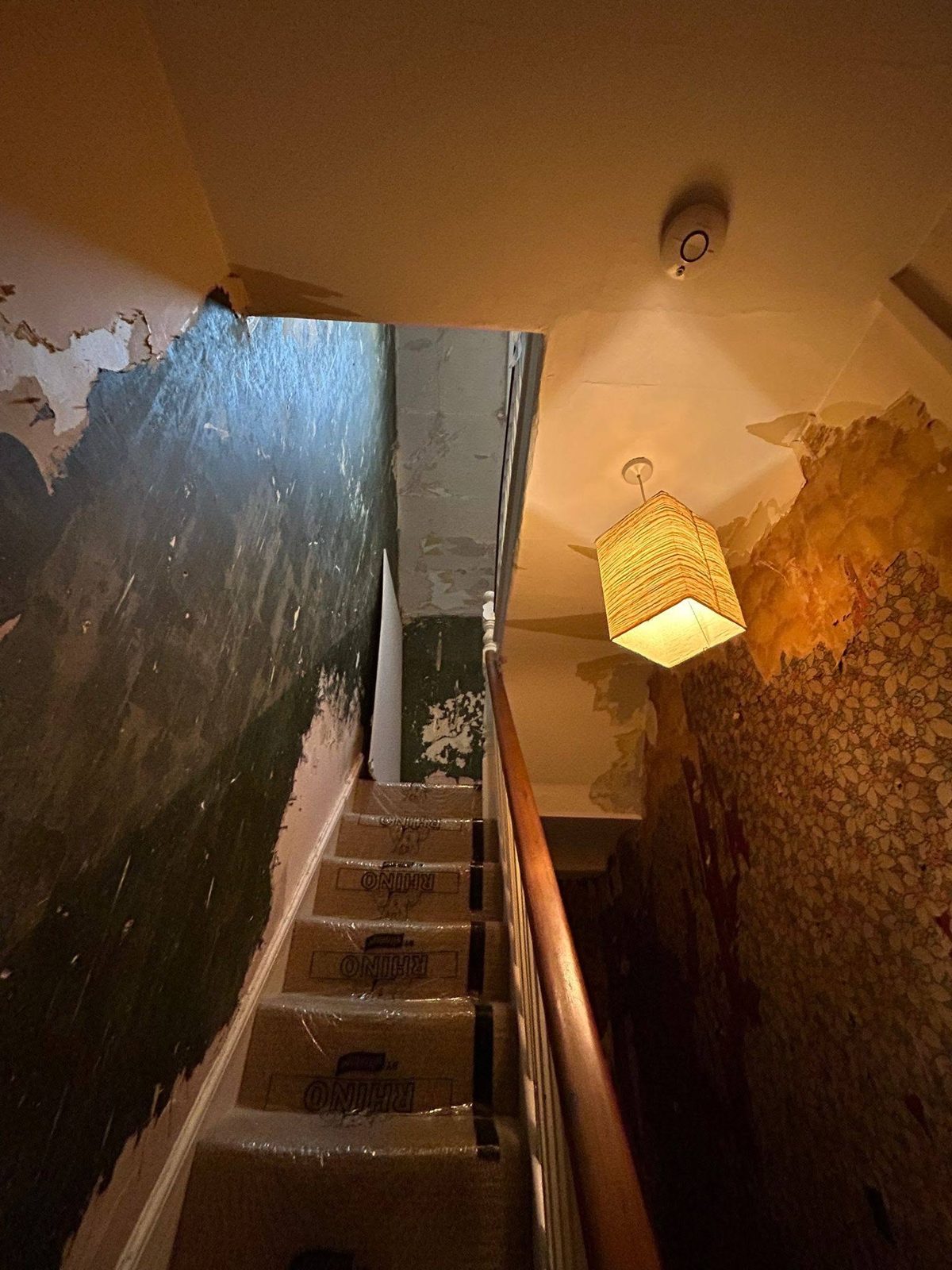 Landing before: dark painted walls flaking, with a lampshade hanging over the stairs