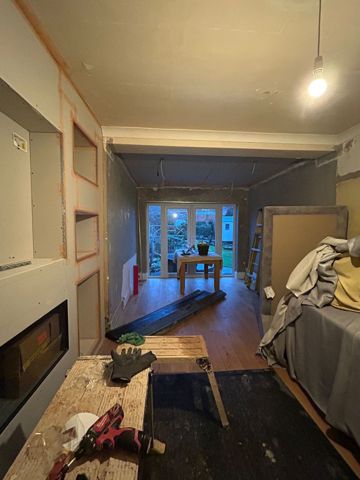 Long through-room with boarded walls, recessed niches and tools on the floor