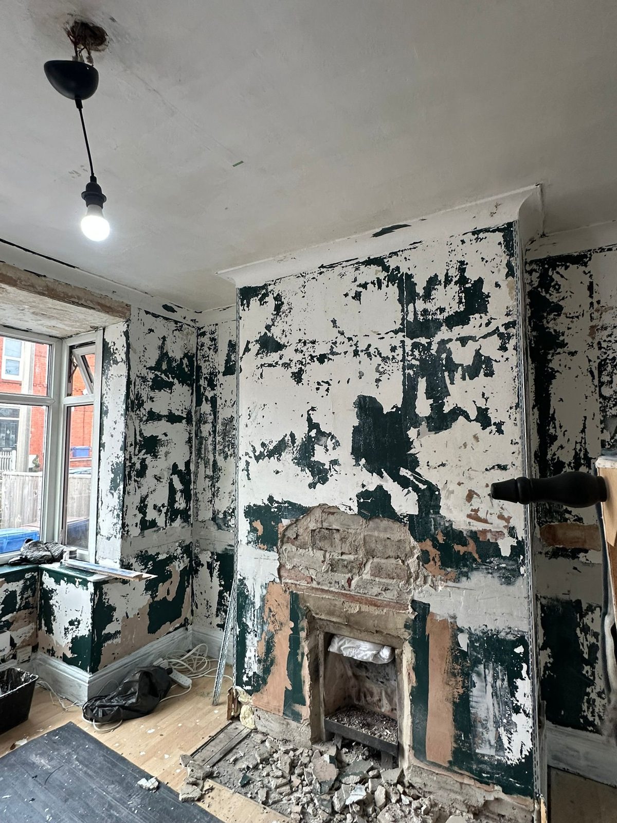Room stripped back with an old fireplace opened up and rubble on the floor